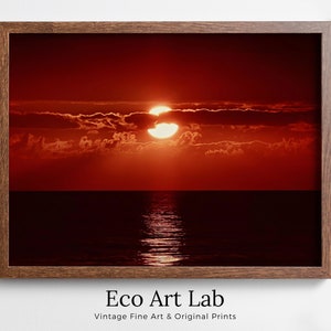Può includere: Un tramonto rosso su un mare calmo con un grande sole luminoso che tramonta dietro le nuvole.