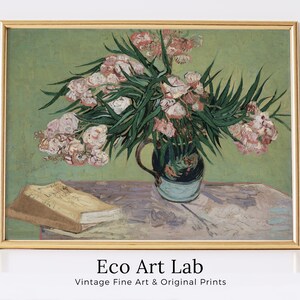 May include: A framed painting of a still life featuring a vase of pink flowers with green leaves on a table with a book. The painting is in a gold frame and has a green background.