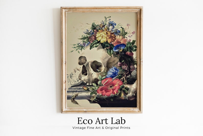 May include: A vintage print of a human skull adorned with a colorful floral wreath. The skull is resting on a table with a few flowers and leaves scattered around it. The print is framed in a light wood frame.