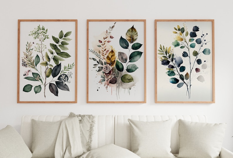 May include: Three framed watercolor paintings of leafy branches with green, blue, and yellow leaves. The paintings are in wooden frames and are hung on a white wall.