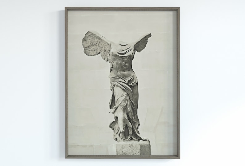 May include: A black and white photograph of the Winged Victory of Samothrace statue, a famous ancient Greek sculpture, displayed in a grey frame.