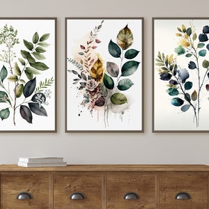 May include: Three framed watercolor prints featuring botanical illustrations of leaves and branches in shades of green, blue, and brown. The prints are arranged in a row on a wall.