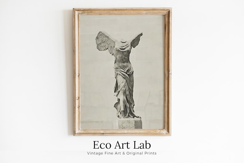 May include: A black and white photograph of the Winged Victory of Samothrace statue, framed in a light wood frame. The image is titled "Eco Art Lab" with the tagline "Vintage Fine Art & Original Prints".