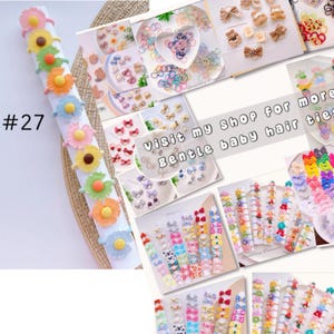 May include: A collection of colorful hair ties featuring various designs, including flowers, bows, and polka dots. The hair ties are arranged on a white background with the text "#27 Visit my shop for more gentle baby hair ties".