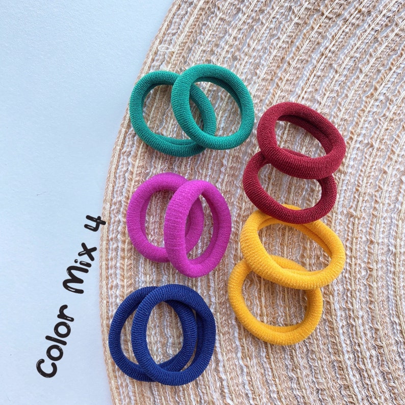 May include: A set of 4 colorful hair elastics in green, red, pink, and yellow. The elastics are arranged on a woven surface. The text "Color Mix 4" is visible in the image.