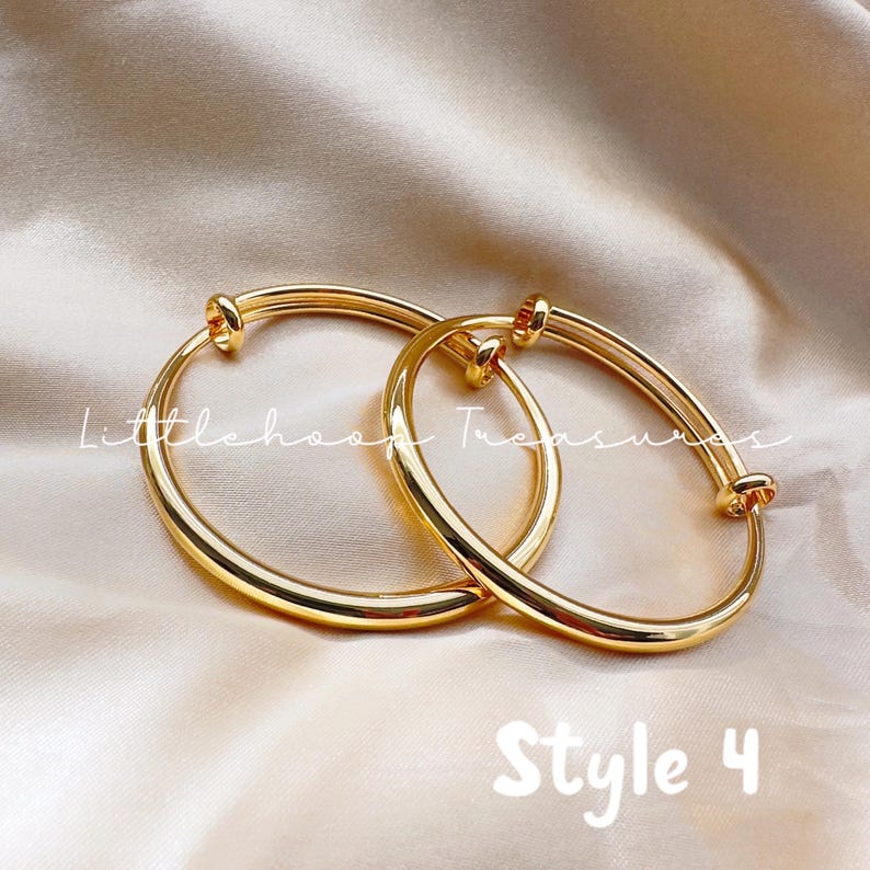 May include: Two gold-colored adjustable bangles. The bangles are round with a smooth, polished finish. The text "Littlehood Treasures" is written in cursive on the top left of the image. The text "Style 4" is written in a playful font at the bottom.