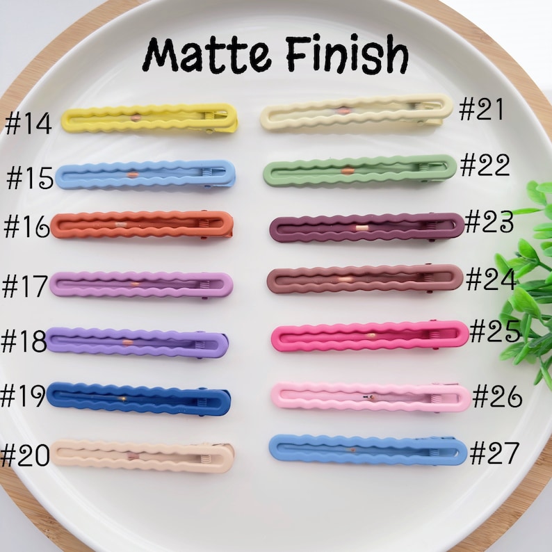 Op de afbeelding: Tien paar matte haarclips in verschillende kleuren, waaronder geel, blauw, groen, bruin, paars, roze en beige. De clips zijn genummerd van 14 tot en met 27.