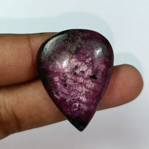 May include: A teardrop-shaped purple gemstone with a swirling pattern and a dark purple edge.