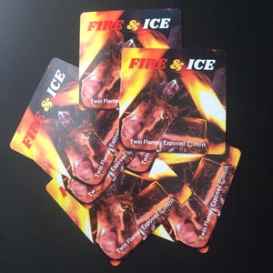 Pu&ograve; includere: Un mucchio di cinque adesivi quadrati con il testo "FIRE & ICE" e le parole "Twin Flames Exposed 2020" stampate su di essi. Gli adesivi presentano uno sfondo arancione e giallo fuoco con un'immagine ravvicinata del viso di una persona.