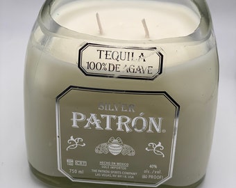 May include: A clear glass candle with two wicks, filled with a light-colored wax. The label reads "SILVER PATRÓN" and "TEQUILA 100% DE AGAVE". The candle is 750 ml and 40% alc./vol. (80 PROOF).