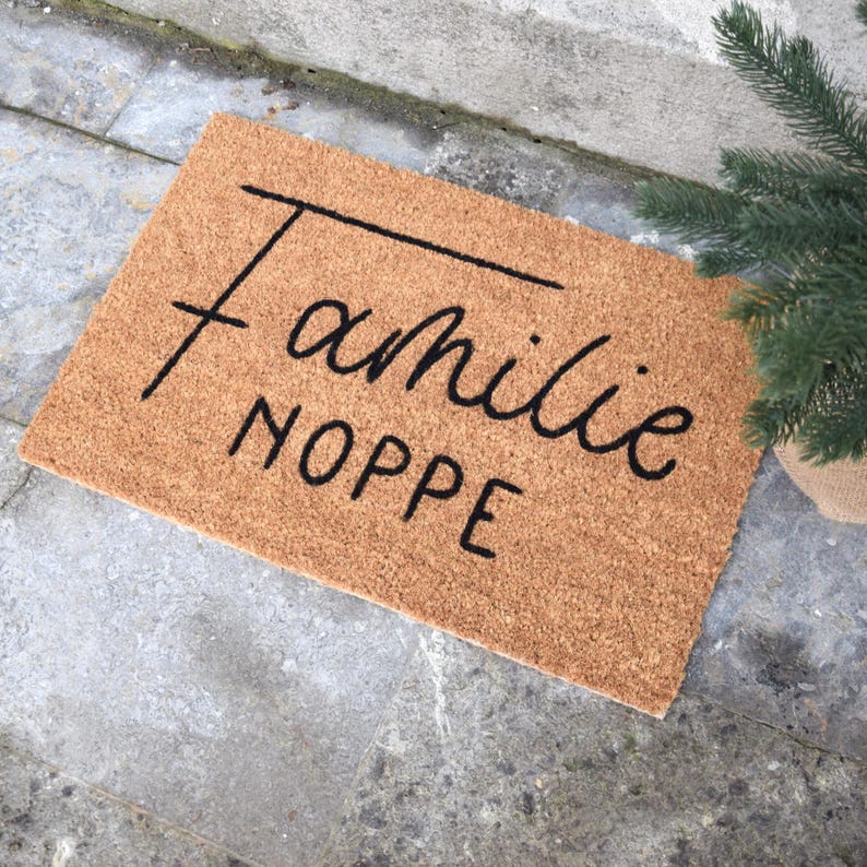 May include: A brown coir doormat with the text "Familie Noppe" in black cursive lettering.