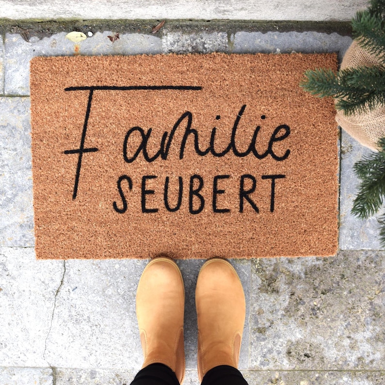 May include: A brown coir doormat with the text "Familie Seubert" in black lettering.