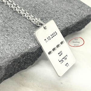 Può includere: Un ciondolo rettangolare in argento sterling 925 su una catena a maglie rotonde abbinata. Il ciondolo è inciso con la data 7.10.2023, una serie di quattro trattini orizzontali e il testo ebraico "עם ישראל חי" in un carattere nero senza grazie.