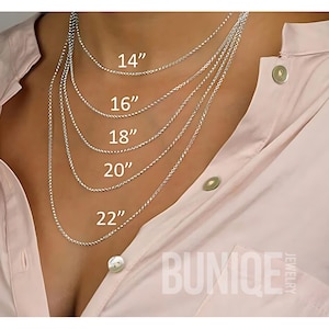 May include: Five silver-toned rope chains displayed in varying lengths of 14, 16, 18, 20, and 22 inches. The text BUNIQE JEWELRY is visible in the bottom right corner. The chains are layered over a light pink collared shirt with buttons.