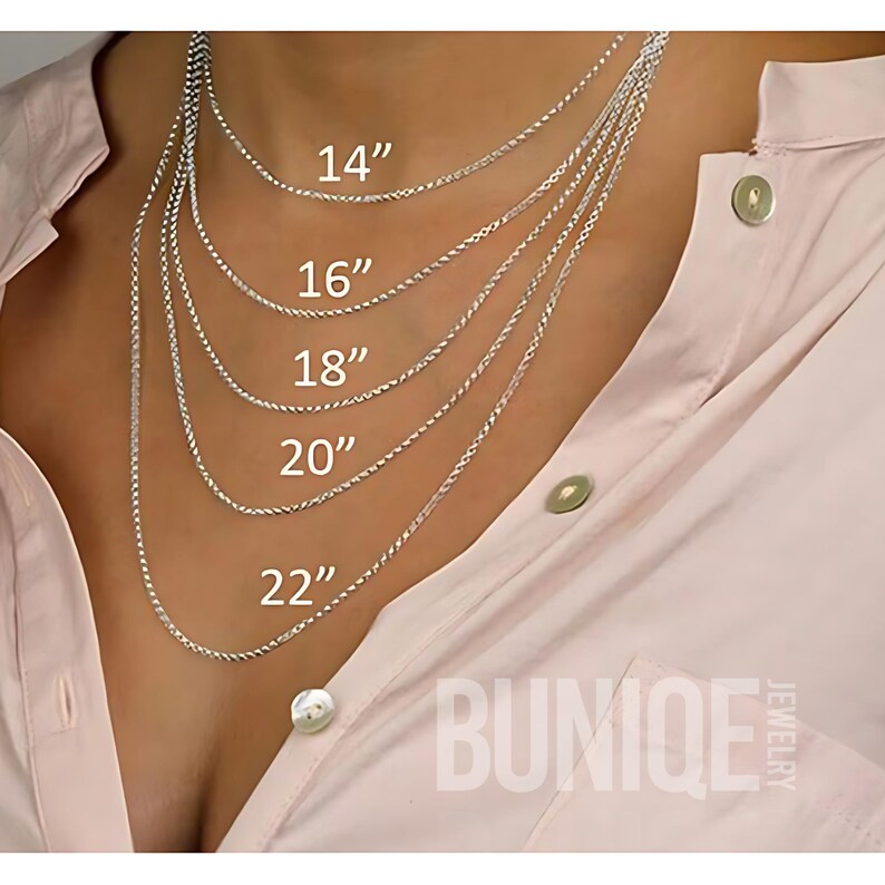 May include: Five silver-toned rope chains displayed in varying lengths of 14, 16, 18, 20, and 22 inches. The text BUNIQE JEWELRY is visible in the bottom right corner. The chains are layered over a light pink collared shirt with buttons.