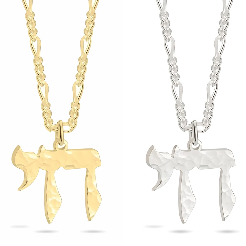 Pu&ograve; includere: Due collane con un ciondolo Chai dalla texture martellata, una in tonalit&agrave; oro e una in tonalit&agrave; argento. Ogni ciondolo &egrave; appeso a una catena a maglie abbinata. Il simbolo ebraico Chai &egrave; chiaramente visibile su entrambi i ciondoli, mostrando una finitura superficiale metallica distinta, riflettente e testurizzata.