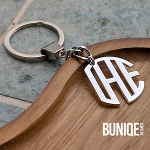 May include: Silver monogram keychain with the letters "HE" in a stylized font. The keychain is attached to a silver ring and chain. The word "BUNIQUE JEWELRY" is printed in white at the bottom of the image.