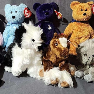 May include: A collection of Beanie Babies plush toys in various colors and animal designs. Includes a pink bear, blue bear, purple bear, brown bear, white dog, brown horse, gray cat, penguin, and a bat.