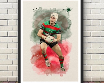May include: A framed watercolor-style art print featuring a rugby player in a red, green, and black jersey and shorts, wearing a protective headgear, holding a rugby ball. The background has abstract green and red paint splatters.