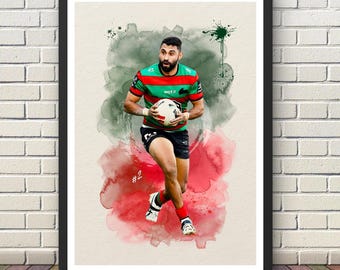 May include: A framed watercolor print of a rugby player in action, holding a ball. The player wears a red, green, and black jersey and black shorts. The background features watercolor splashes of red, green, and white. The print is displayed on a white brick wall.