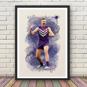 May include: A framed watercolor print of a football player in a purple and white uniform, celebrating a victory. The artwork features a splash of purple watercolor in the background, with the text "EST 94" and the player's name and number.