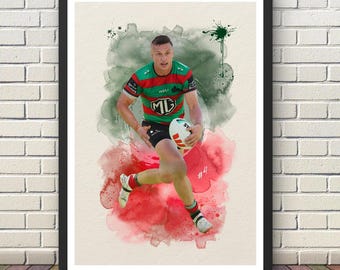 May include: A framed watercolor print of a rugby player in action, holding a ball and running. The player is wearing a green, red, and black jersey. The background features watercolor splashes of red and green.