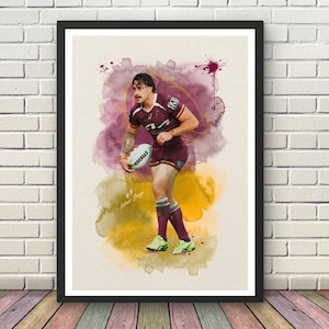 May include: A framed art print featuring a watercolour-style illustration of a rugby player in a maroon jersey and shorts, holding a Steeden ball. The player wears number 3, with the text #3 Kotoni Staggs visible. The background has purple and yellow splashes.