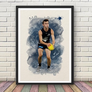 May include: A framed art print featuring a watercolour-style illustration of an Australian rules football player in a dark navy uniform holding a yellow ball. The player is centred against a blue ink wash background with the text #7 Jagga Smith.