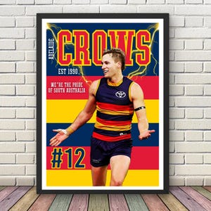 Könnte beinhalten: Gerahmtes Poster mit einem Athleten in einer marineblauen, gelben und roten Uniform. Das Poster trägt die Aufschrift "ADELAIDE CROWS EST 1990" und "WE'RE THE PRIDE OF SOUTH AUSTRALIA." Das Trikot des Athleten hat die Nummer 12.