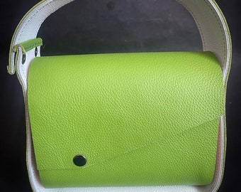 May include: A small green leather handbag with a white leather strap. The bag has a single snap closure.