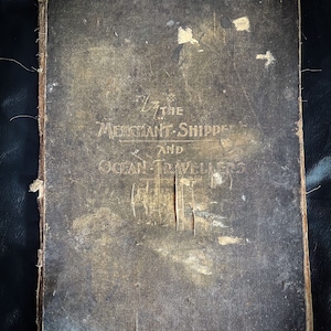 May include: A worn, dark brown leather-bound book with the title "For the Merchant-Shippers and Ocean-Travellers" embossed on the front cover.