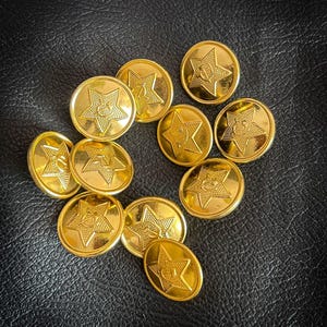 May include: A group of ten gold-coloured metal buttons with a five-pointed star design. Each star has a smaller design inside.