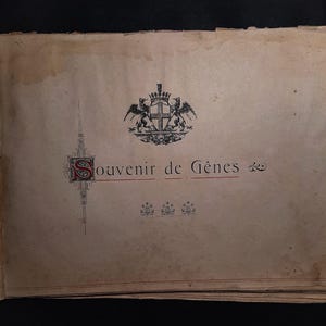 May include: A vintage book cover with a black and white illustration of a coat of arms featuring a cross and two lions. The text "Souvenir de G&ecirc;nes" is printed in red and black.