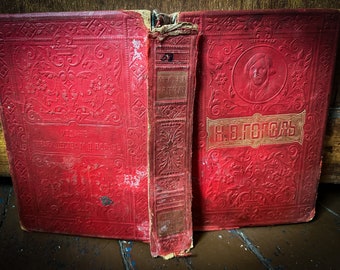 May include: A red, worn book with gold lettering on the cover. The title is "Сочинения Н.В. Гоголя" (Works of N.V. Gogol).