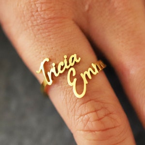 May include: Gold ring with the names "Tricia" and "Emma" written in cursive.