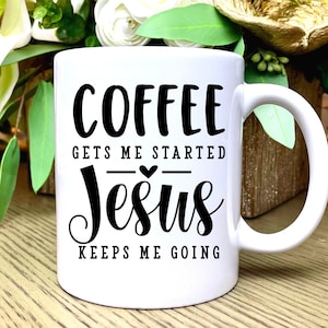 K&ouml;nnte beinhalten: Wei&szlig;e Keramik-Kaffeetasse mit schwarzem Text, der "Coffee gets me started Jesus keeps me going" lautet. Ein kleines Herz befindet sich zwischen den W&ouml;rtern "started" und "Jesus".