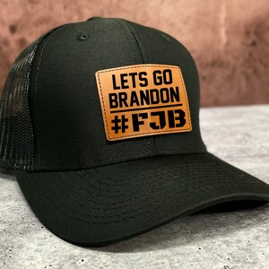 May include: Black trucker hat with a brown leather patch that says "Lets Go Brandon #FJB"