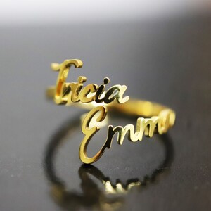 May include: Gold ring with the names "Tricia" and "Emma" written in cursive.