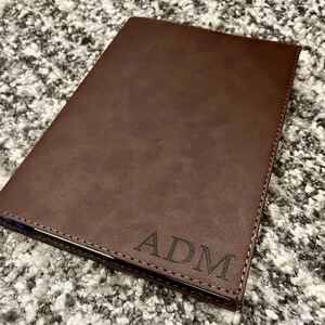 May include: A brown leather notebook with the initials "ADM" embossed on the front cover.