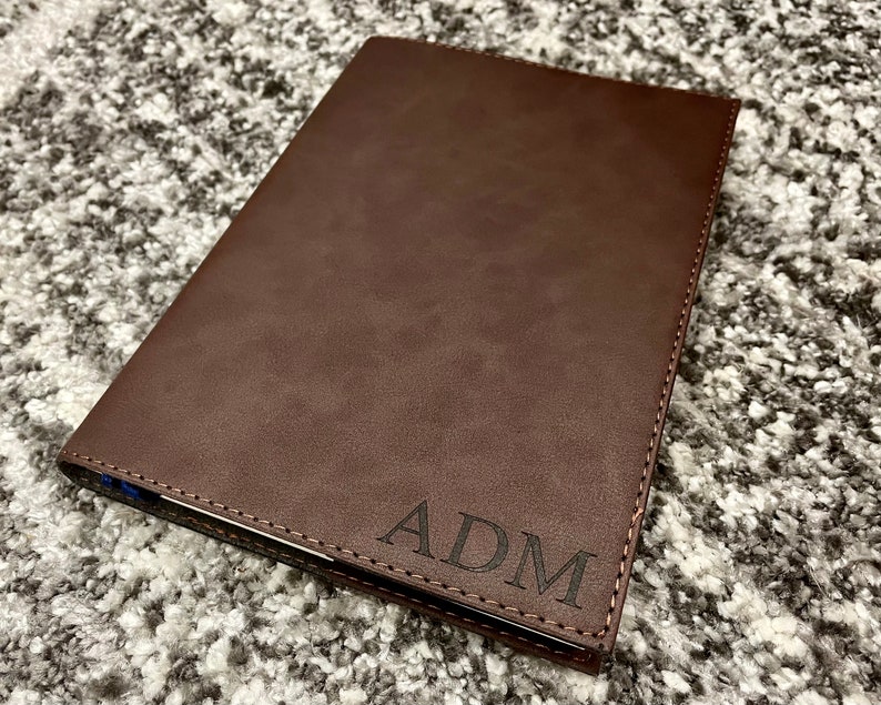 May include: A brown leather notebook with the initials "ADM" embossed on the front cover.