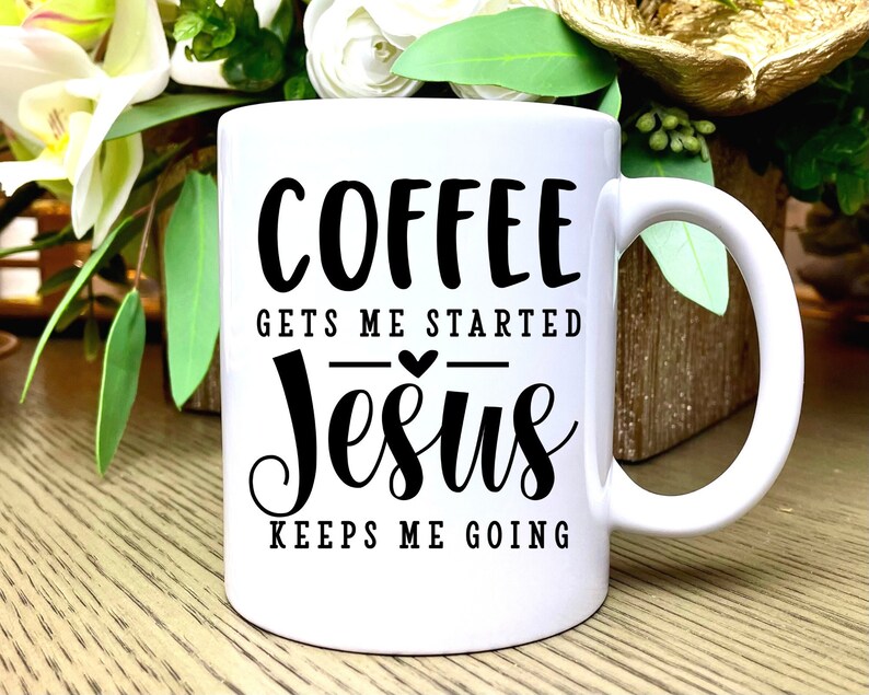 K&ouml;nnte beinhalten: Wei&szlig;e Keramik-Kaffeetasse mit schwarzem Text, der "Coffee gets me started Jesus keeps me going" lautet. Ein kleines Herz befindet sich zwischen den W&ouml;rtern "started" und "Jesus".