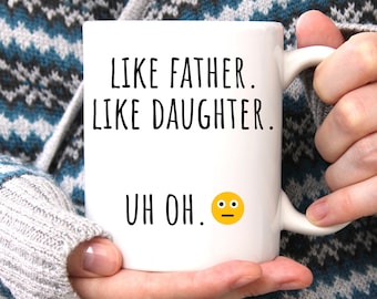 Pode incluir: Caneca de café de cerâmica branca com texto preto que diz "Like father. Like daughter. Uh oh." e um emoji amarelo com uma expressão confusa.