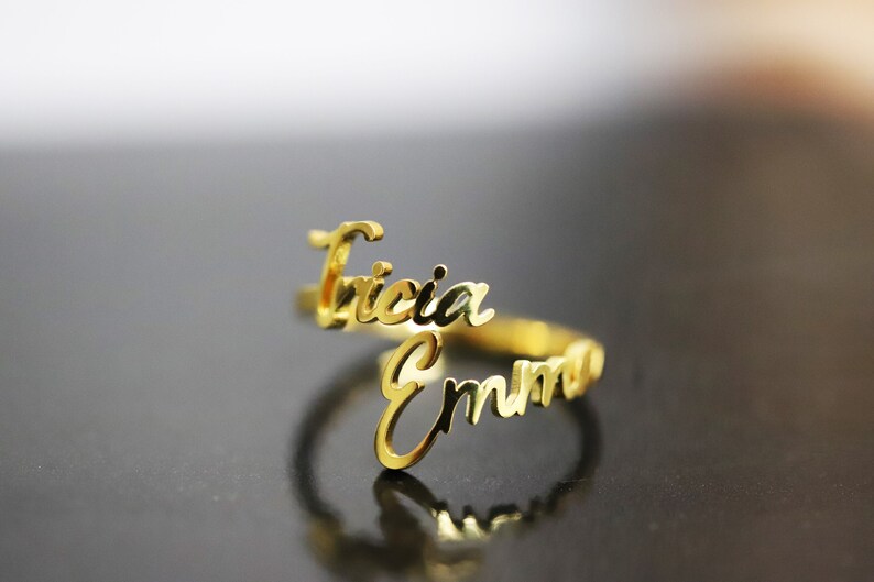 May include: Gold ring with the names "Tricia" and "Emma" written in cursive.