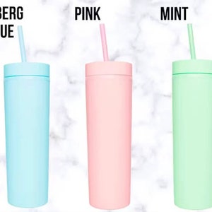 Puede incluir: Tres vasos aislados en Azul Iceberg, Rosa y Menta, cada uno con una pajita a juego. Los vasos son cil&iacute;ndricos y tienen un acabado mate. El texto "ICEBERG BLUE", "PINK" y "MINT" est&aacute; impreso encima de cada vaso.