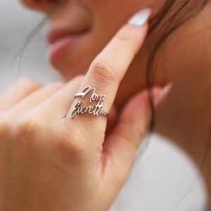 May include: A silver ring with the names "Nora Everett" written in cursive script.