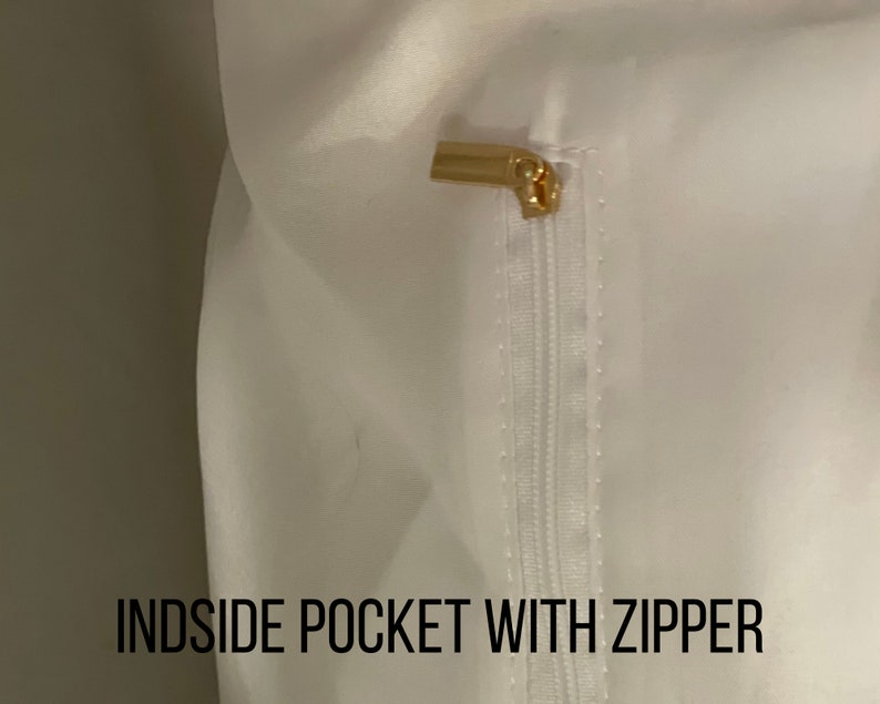 May include: White fabric with a zippered pocket. The zipper pull is gold metal.