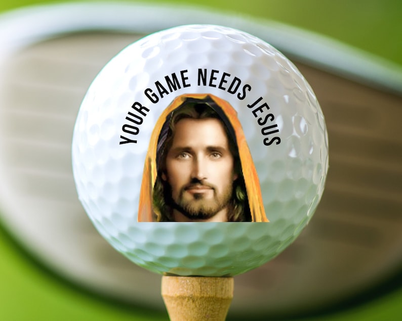 May include: A white golf ball with a picture of Jesus on it. The text "Your game needs Jesus" is printed around the image.