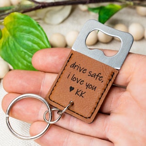 May include: Brown leather keychain with a silver bottle opener. The keychain has the text "drive safe, i love you  KK" engraved on it.