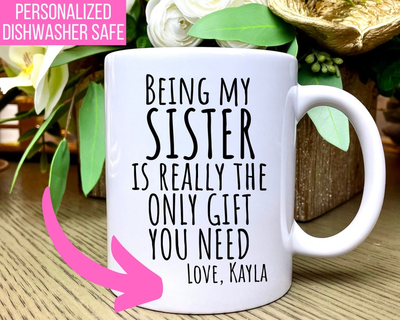 K&ouml;nnte beinhalten: Wei&szlig;e Keramiktasse mit schwarzem Text, der lautet: "Meine Schwester zu sein, ist wirklich das einzige Geschenk, das du brauchst. Liebe, Kayla".