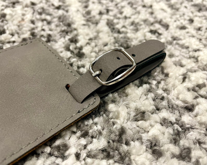 Peut inclure: Une &eacute;tiquette &agrave; bagages en cuir gris avec une boucle en m&eacute;tal argent&eacute;. L'&eacute;tiquette est cousue sur les bords.